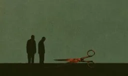 two men looking at some red scissors 