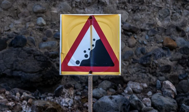 A cliff edge sign against a cliff